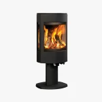 En modern svart vedeldad kamin med glaspaneler som visar en ljus eld inuti, monterad på en piedestal, mot en vit bakgrund.