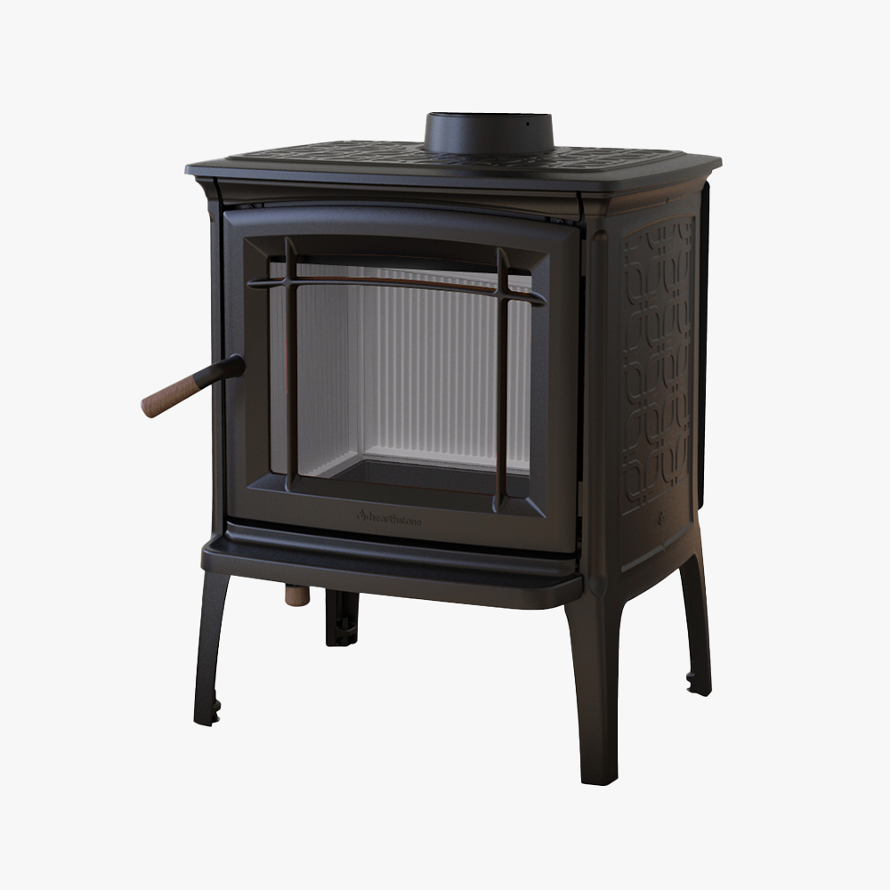 Hergom Craftsbury HF är en vedeldad kamin i svart gjutjärn med glasdörr, sidohandtag och dekorativa sidomönster, med fyra robusta ben och visas mot en vit bakgrund.