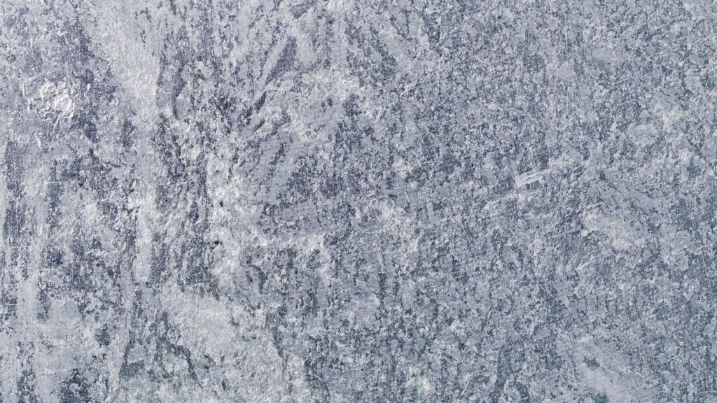 Grov, strukturerad grå stenyta med marmorerade mönster och fläckar av ljusare och mörkare nyanser - perfekt för dig som vill rengöra täljsten och behålla dess naturliga skönhet.