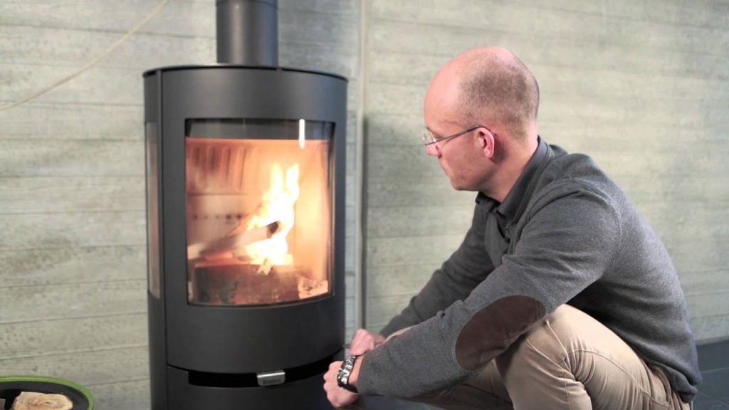 Man sitter framför felaktig braskamin som brinner fint.
