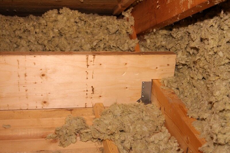 Vanliga fel vid installation (och hur du undviker dem) 2 Lös glasfiberisolering på en vind omger träbjälkar och ramverk. Isoleringen fyller ut mellanrummen mellan träet för att hjälpa till med temperaturregleringen.